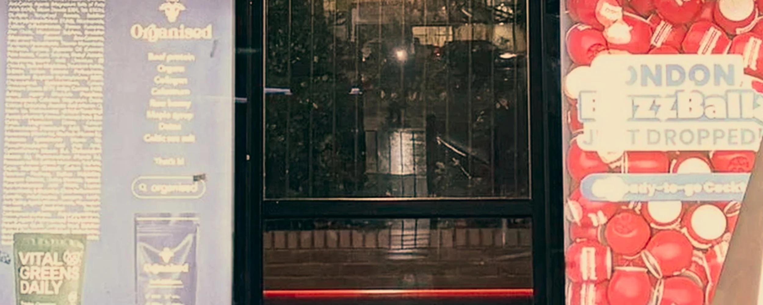 A vending machine with a clear glass panel revealing snacks and a sign on the side with text about the store.