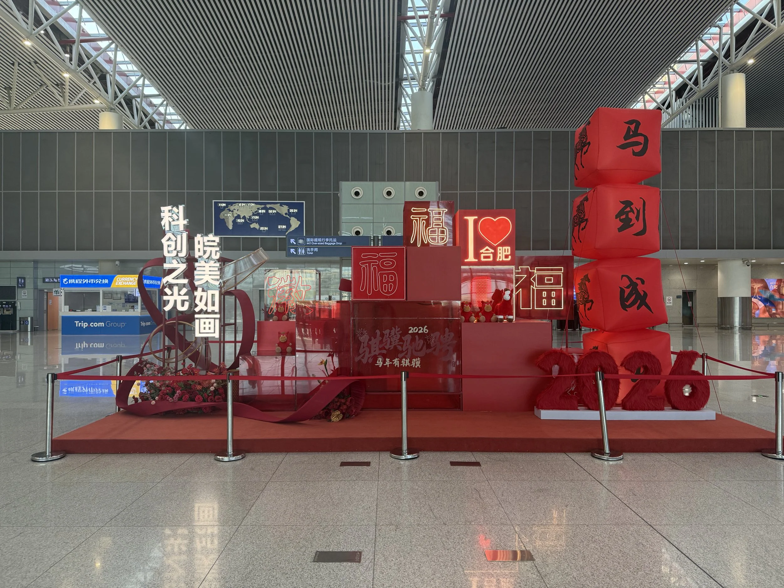 Decorative display at an indoor public space with red lanterns, Chinese characters, teddy bears, and floral arrangements, likely celebrating the Chinese New Year.