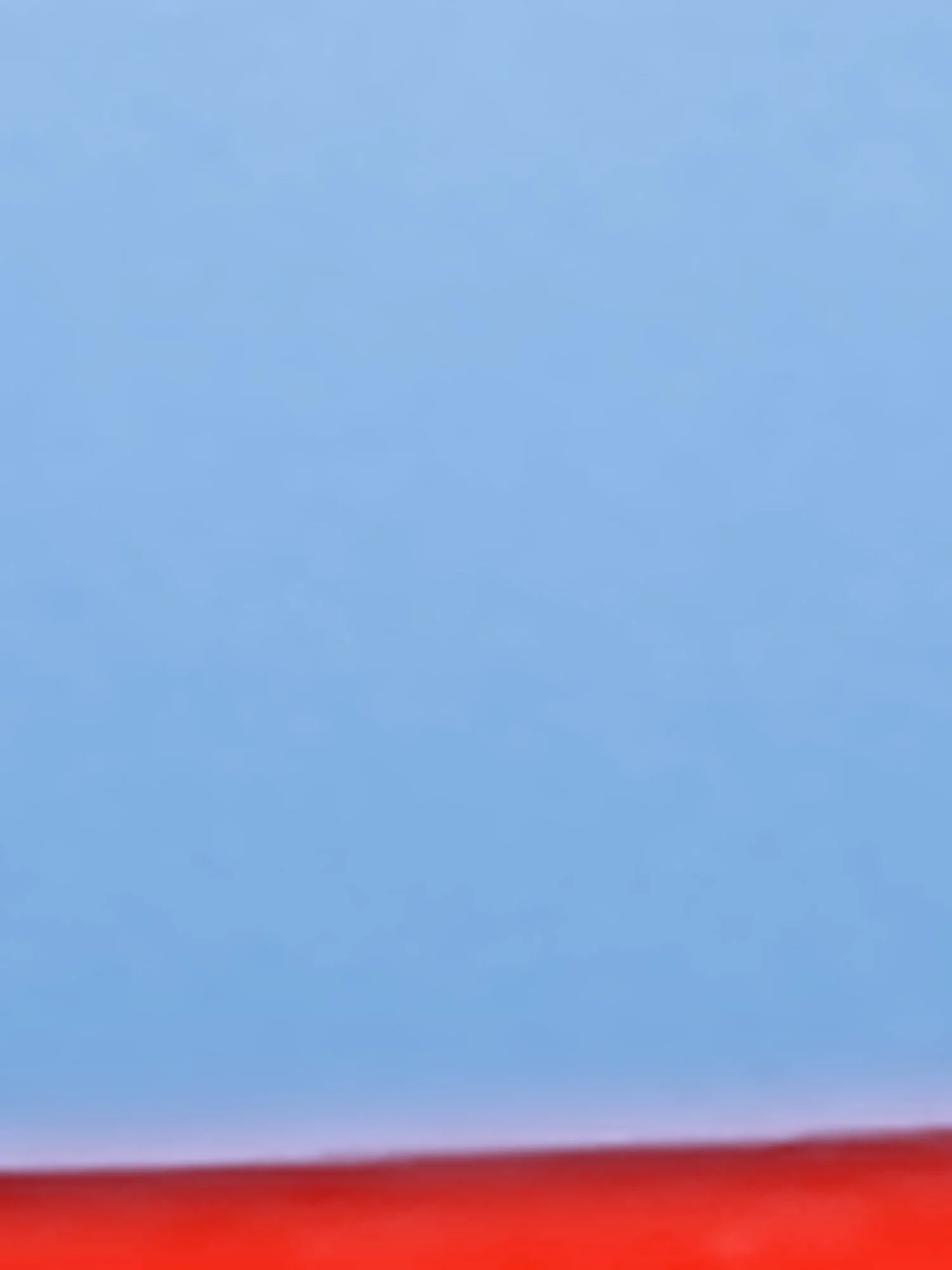 A blurred abstract landscape with a gradient sky transitioning from blue at the top to pink at the bottom, possibly during sunset or sunrise.