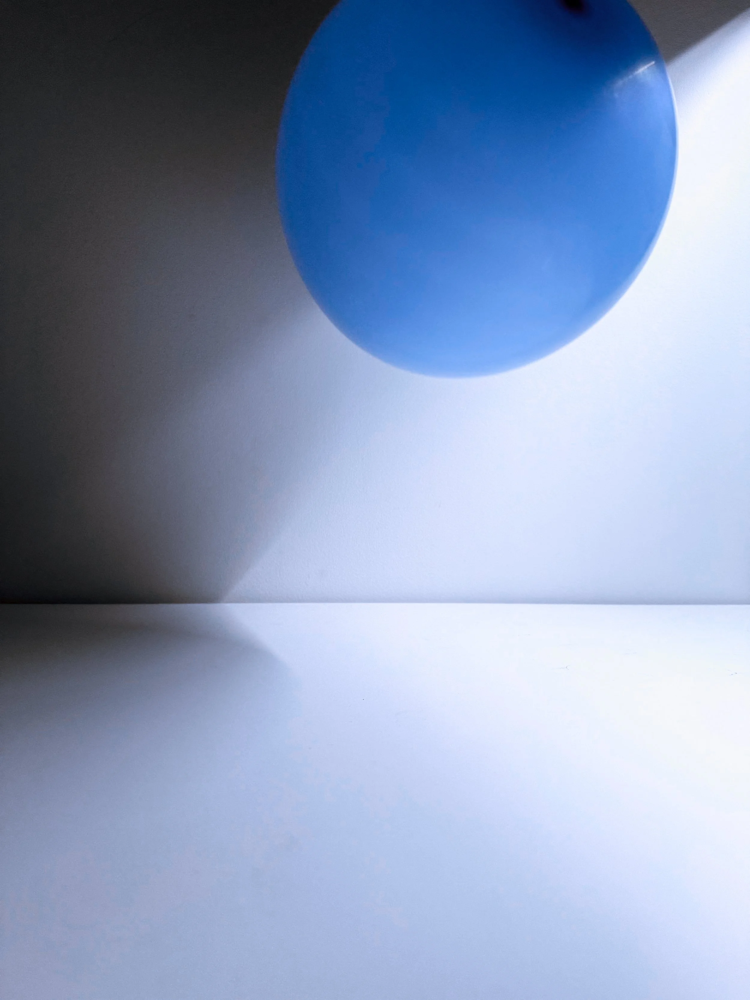 Black background with a large blue circular shape in the center, casting shadow on a white surface below.