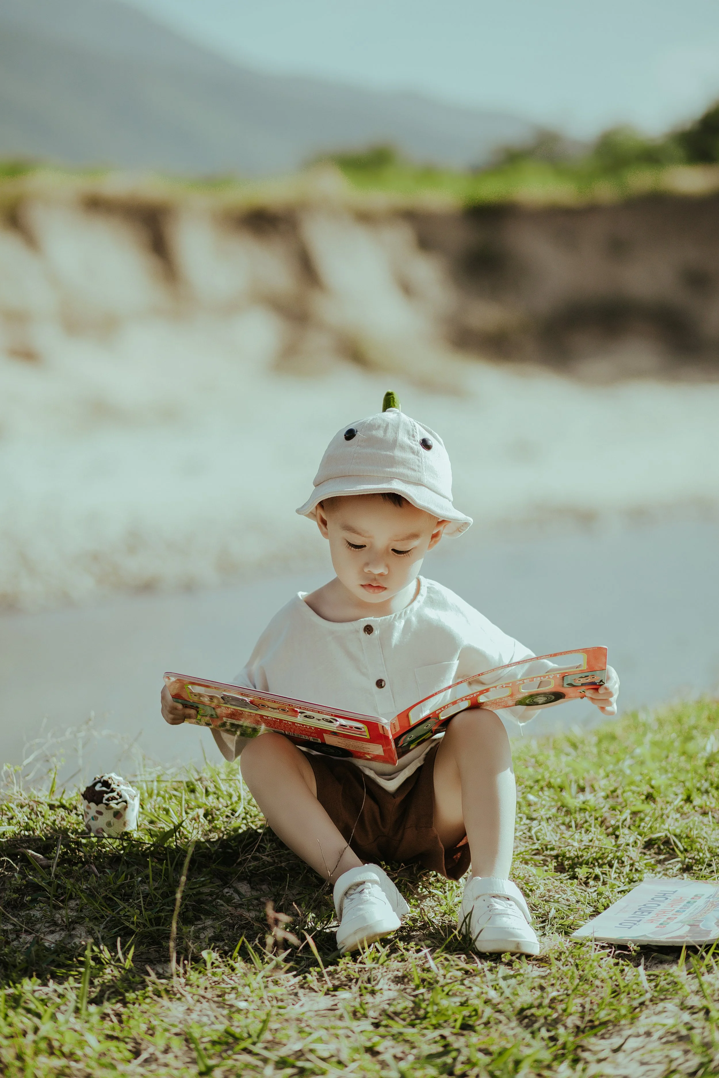 A boy reading outside in the grass