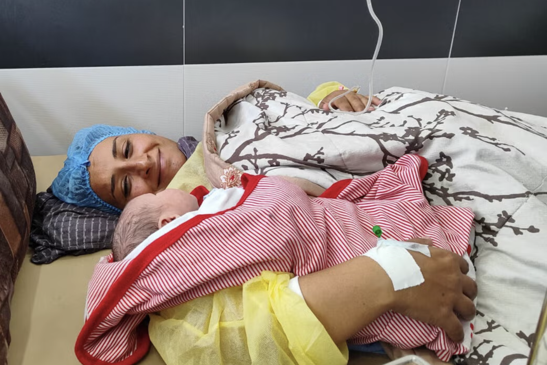 Newborn baby wrapped in mother's arm