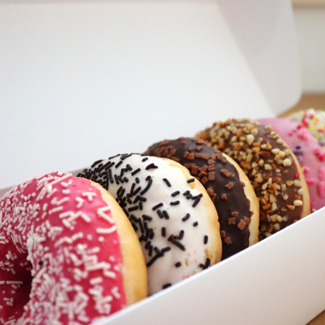 A box of assorted frosted donuts with various sprinkles and toppings.