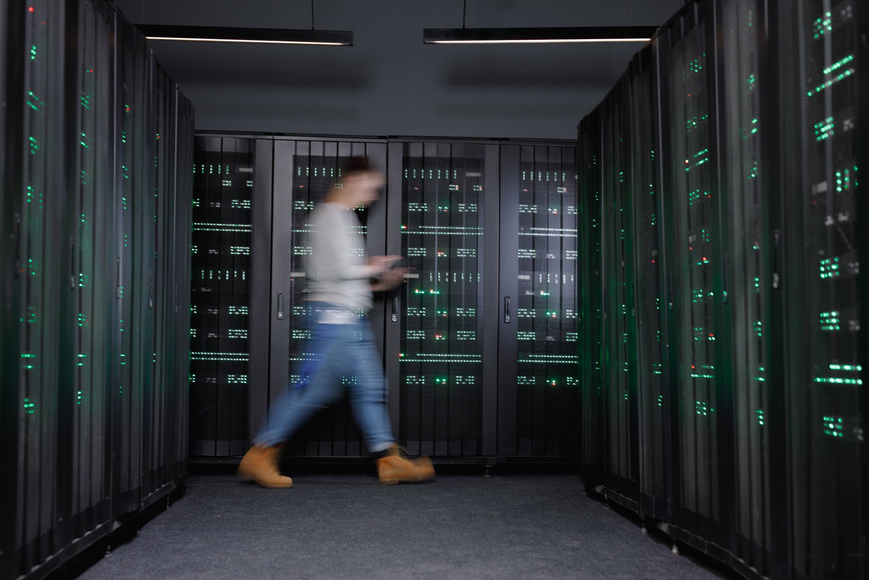 Individual walking through data center with a tablet in hand