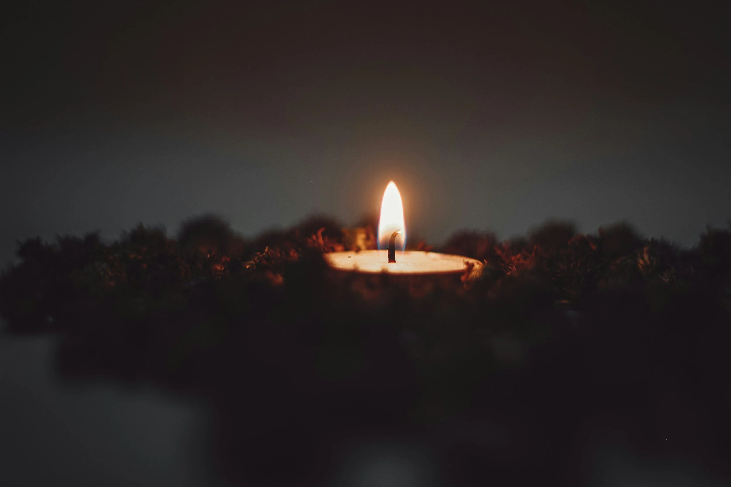 Close-up of a lit candle on a dark background.