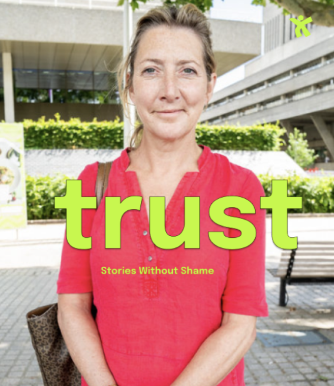 A woman with light brown hair and blue eyes standing outdoors in front of greenery and modern architecture, wearing a red top and carrying a leopard print bag. The word "trust" is in large green letters, with the phrase "Stories Without Shame" underneath.