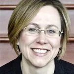 A woman with short blonde hair, glasses, and a big smile.