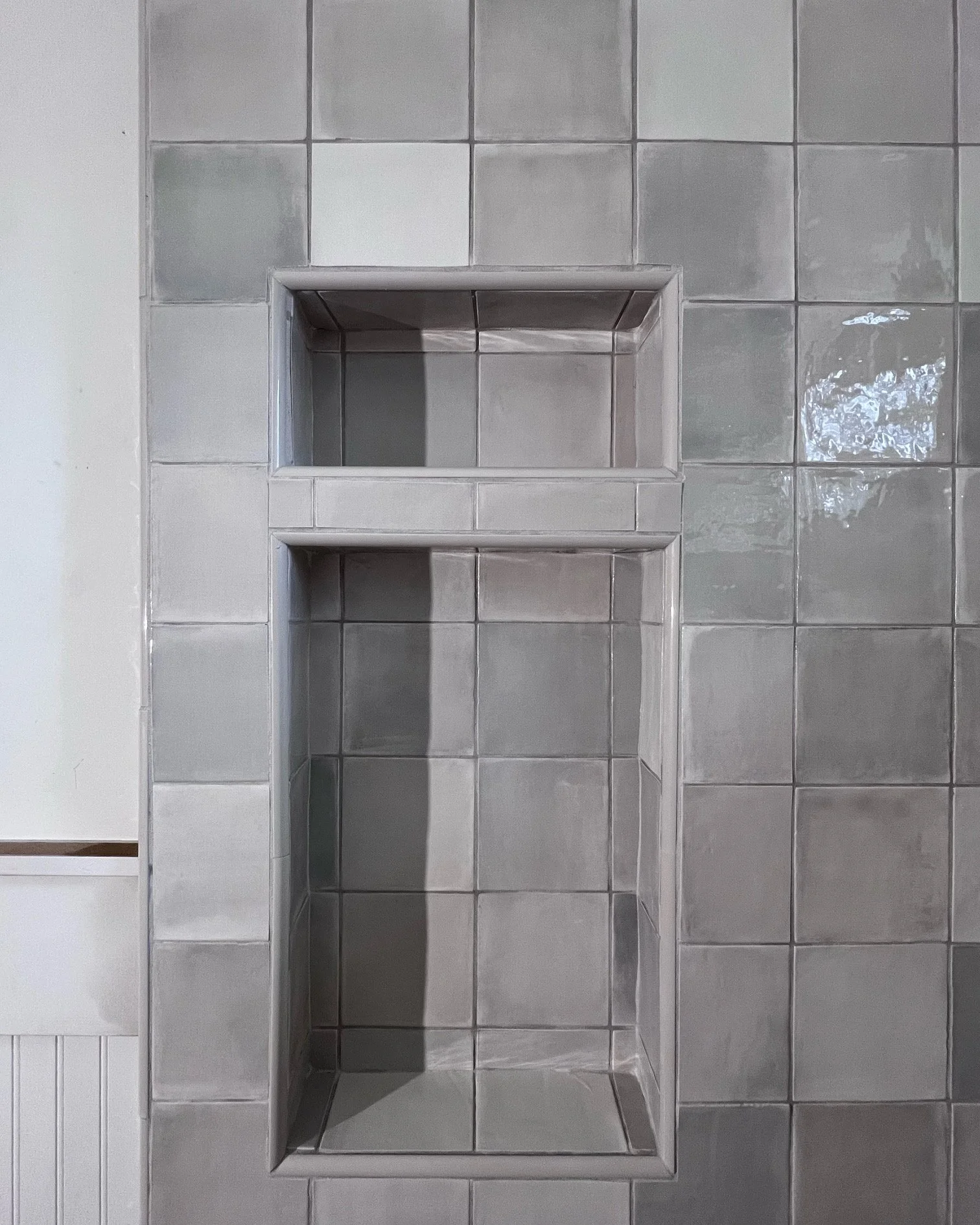 Empty built-in shower niche with tiled walls and floor in a bathroom.