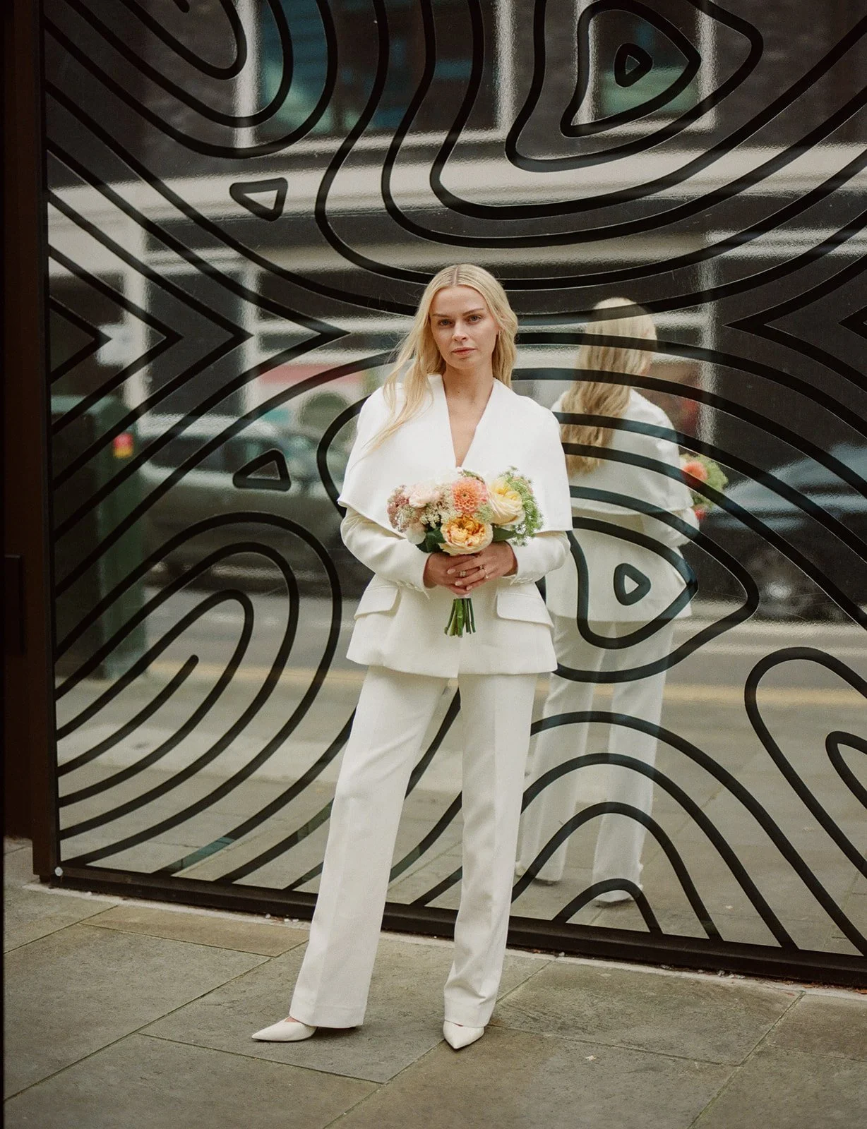 Chic editorial portrait of a bride in a white suit in London.