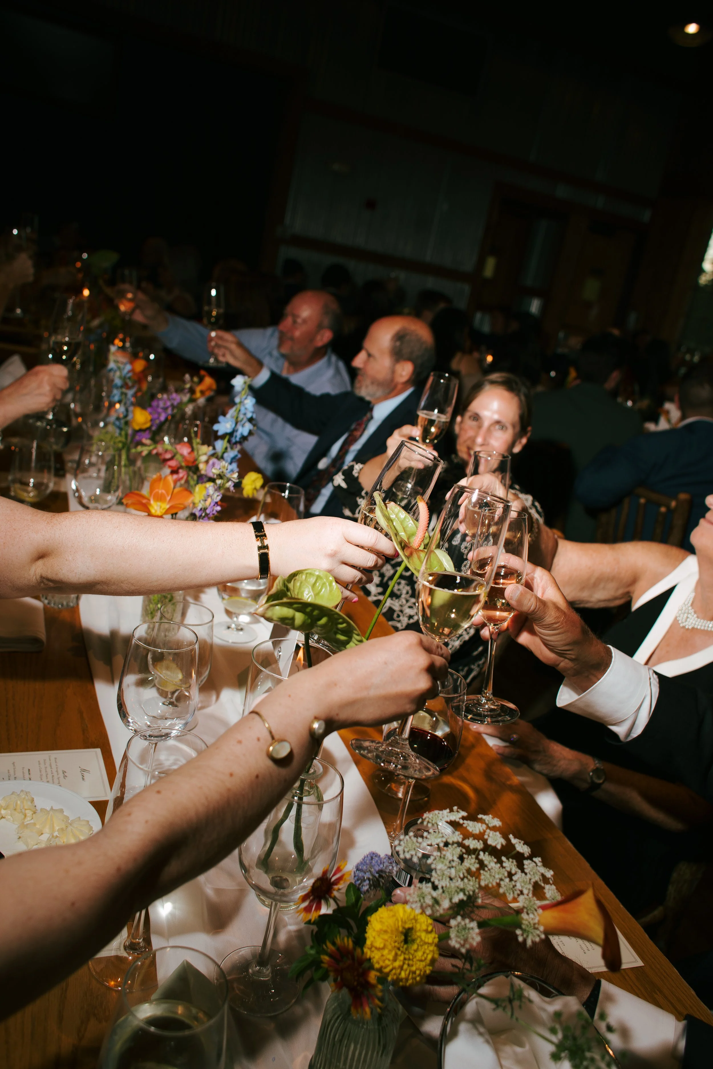 A candid flash photo of guests clinking glasses during a wedding in Colorado.