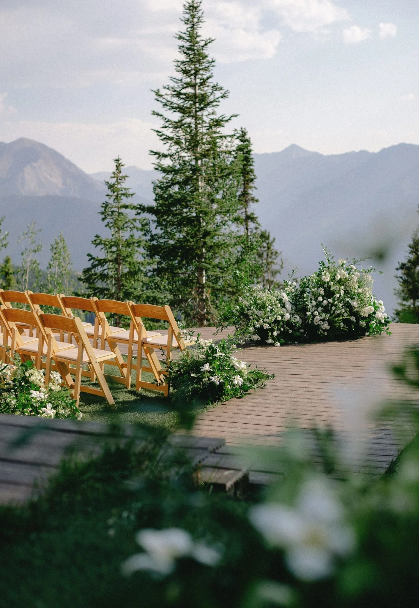 The Little Nell wedding deck decorated with white flowers and lush greenery for an evening ceremony.