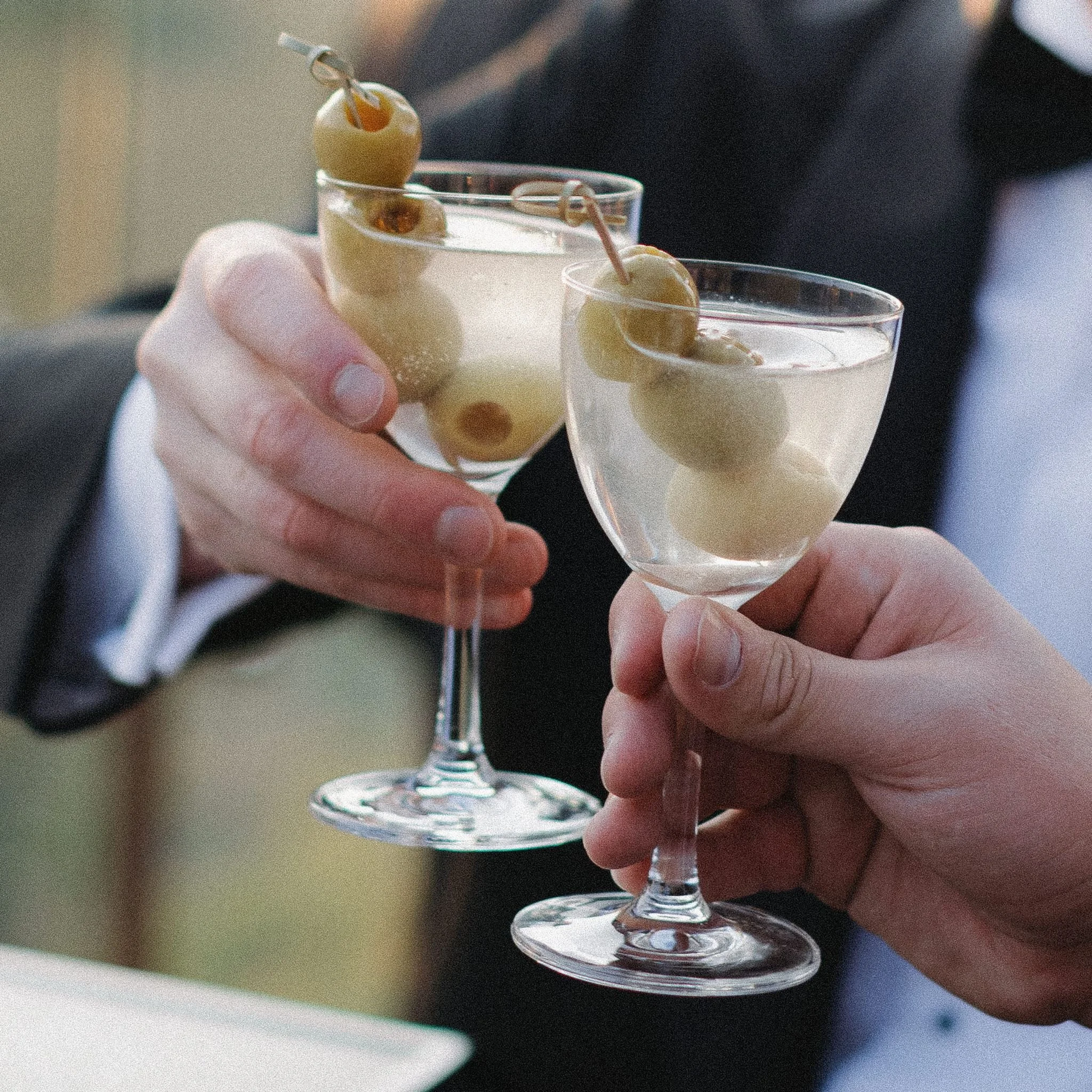 Aesthetic photo of two wedding guests clicking their dirty martinis.
