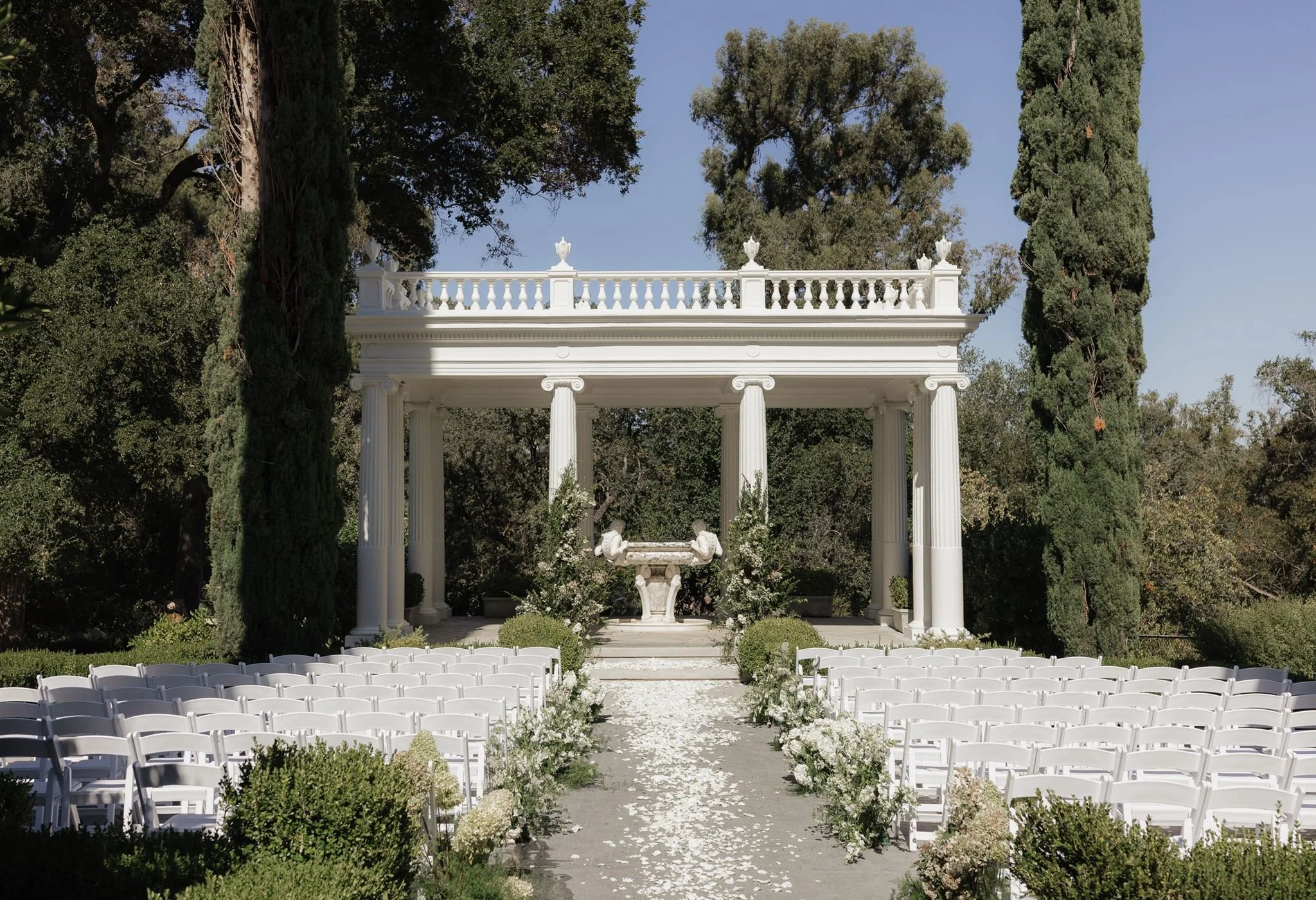 A wide photo of the ceremony space at Villa Montalvo in California, decorated with white flowers and lush greenery.
