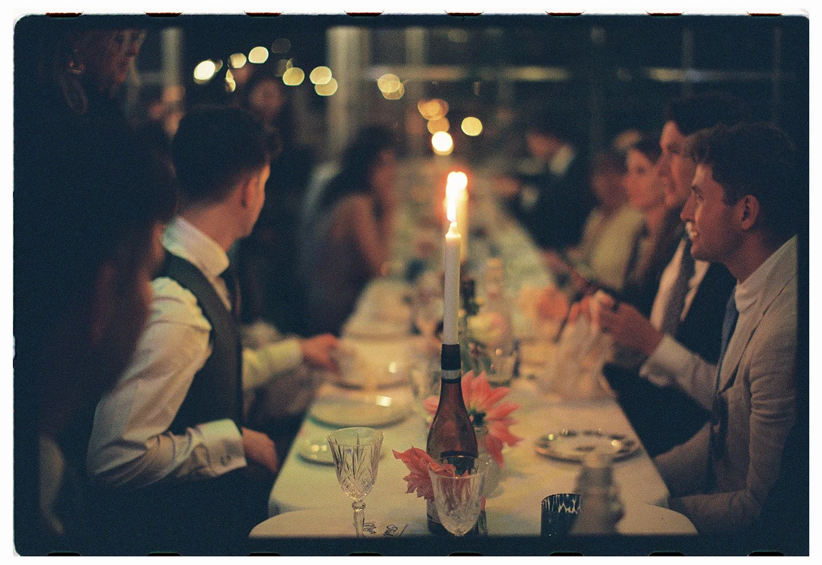 Wedding guests gathered around an intimate dinner table in the Costwolds.