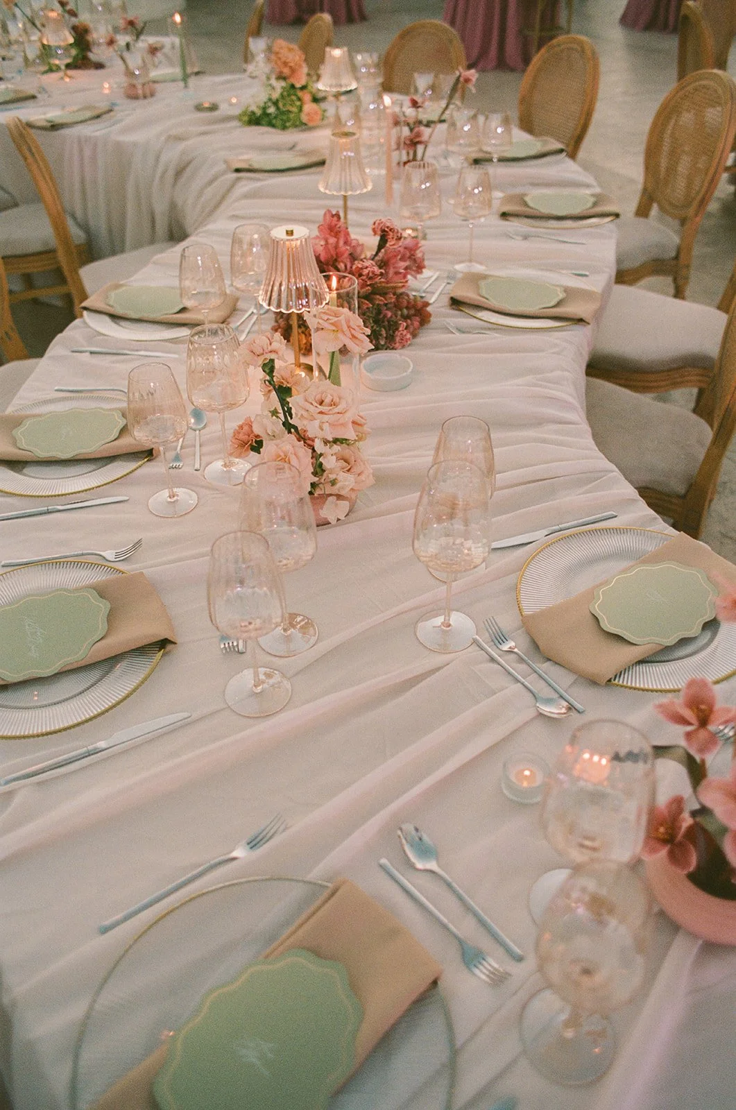 A modern curvy wedding reception table set with orchids and stylish lamps.