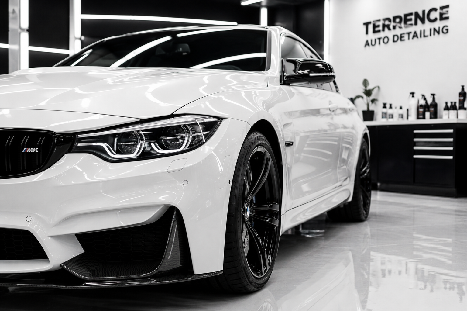 White BMW M4 car inside an auto detailing shop with black accents, black wheels, and a sign that reads 'Terrence Auto Detailing' on the wall.