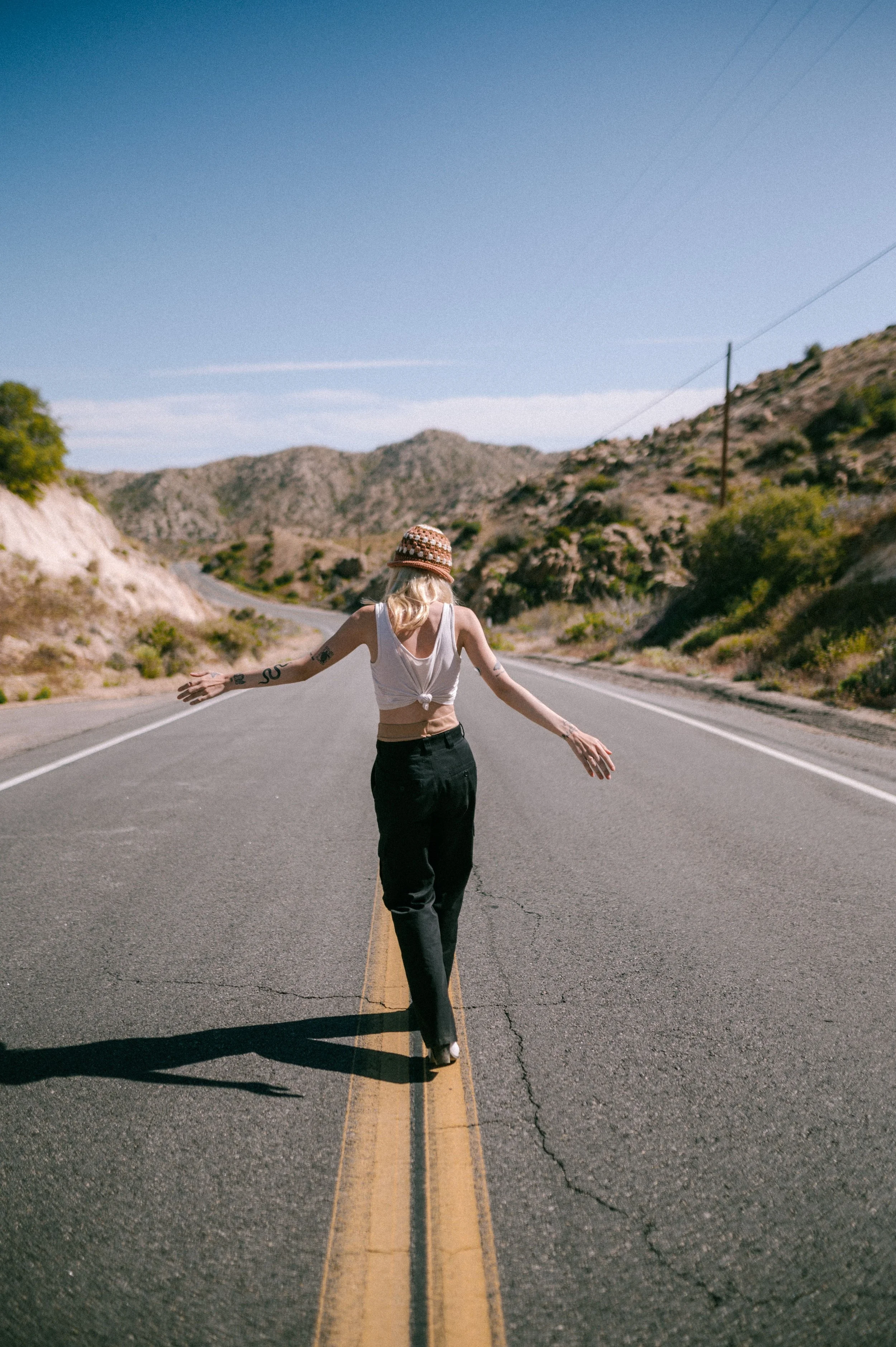 Back view of a Woman Walking in the middle of the road in the desert