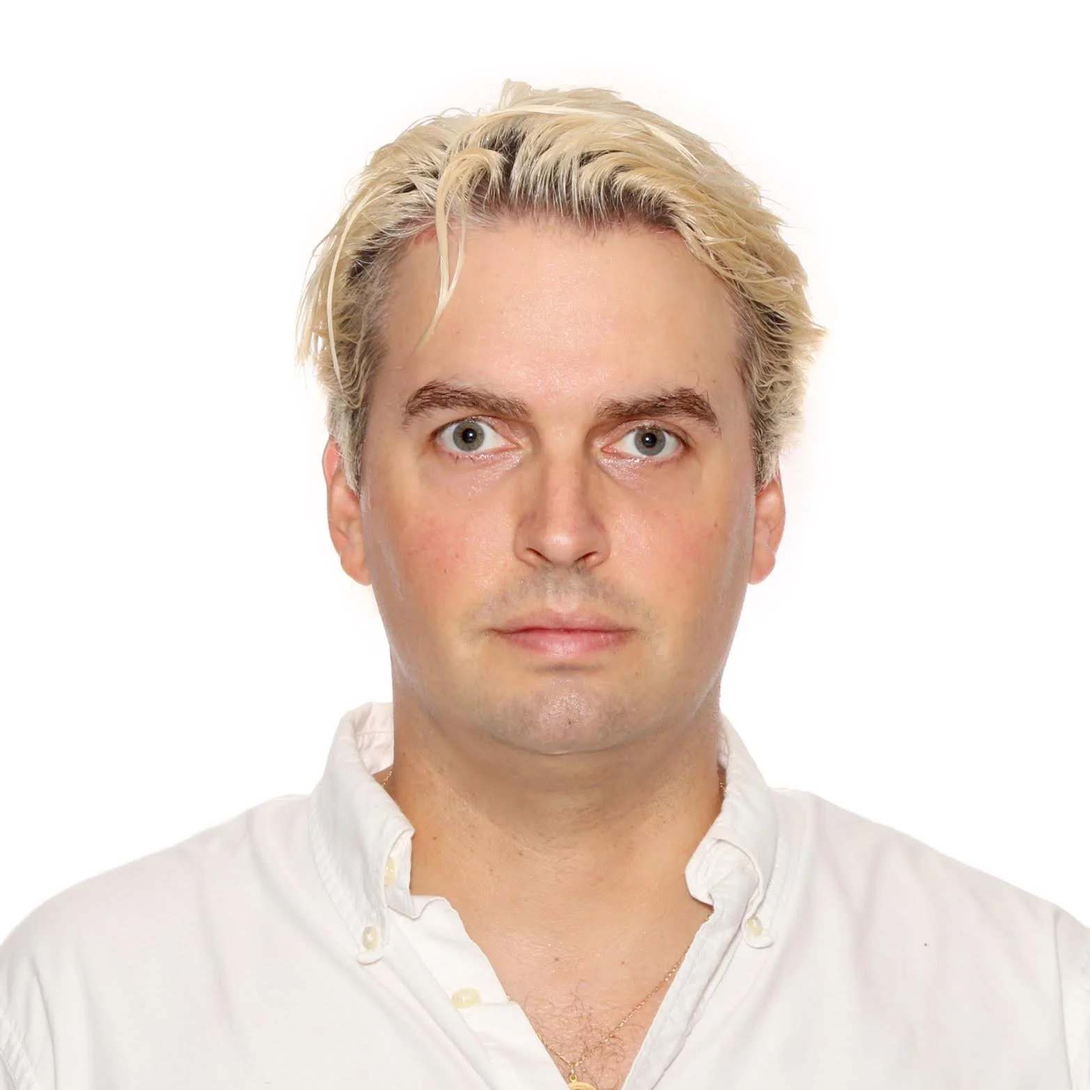A young man with blonde hair, blue eyes, and fair skin wearing a white button-up shirt. He is looking directly at the camera with a neutral expression. The background is plain white.