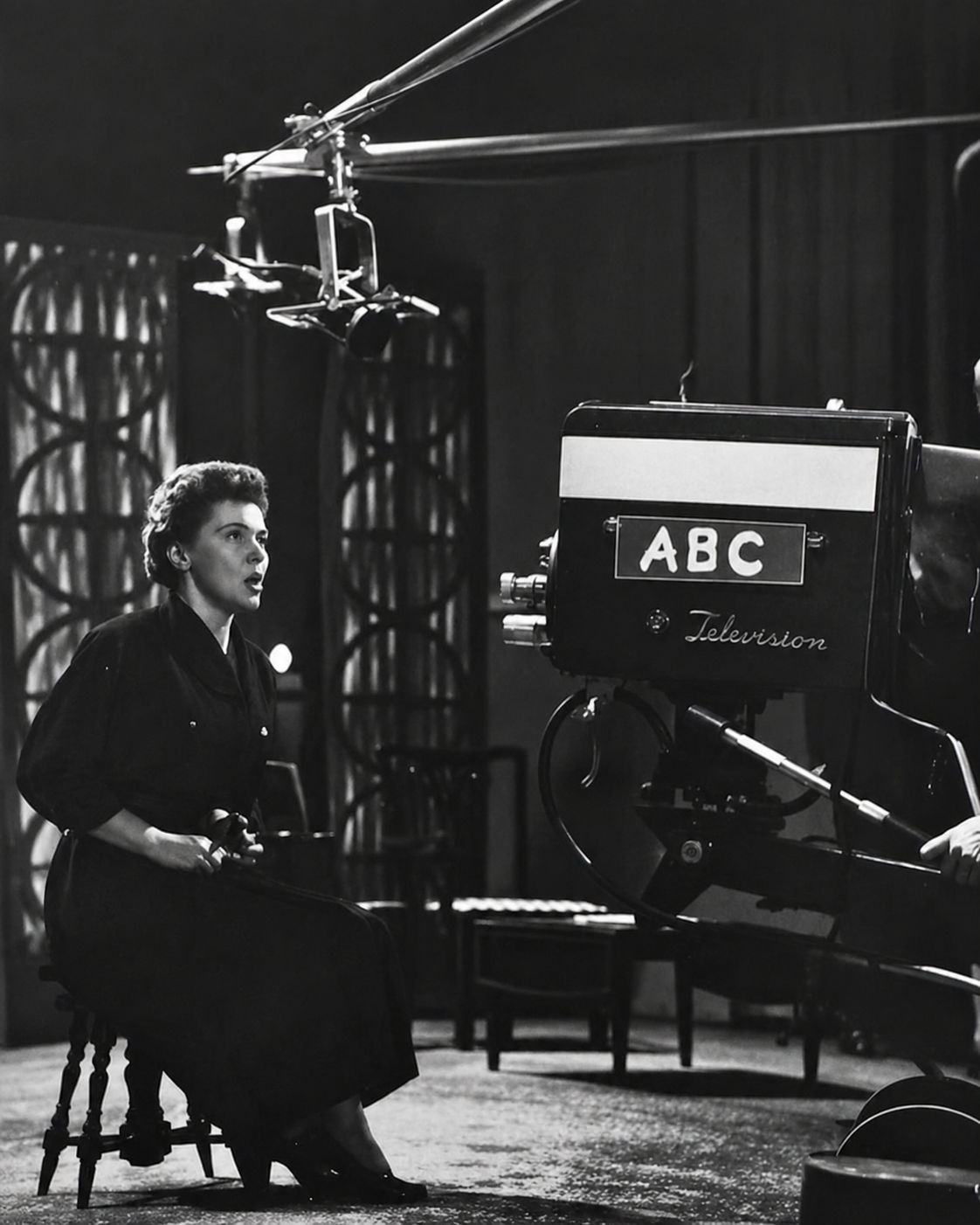 Black-and-white photo of Ethel Barrett seated in an ABC television studio performing in front of a vintage camera, during her broadcasting and storytelling career.