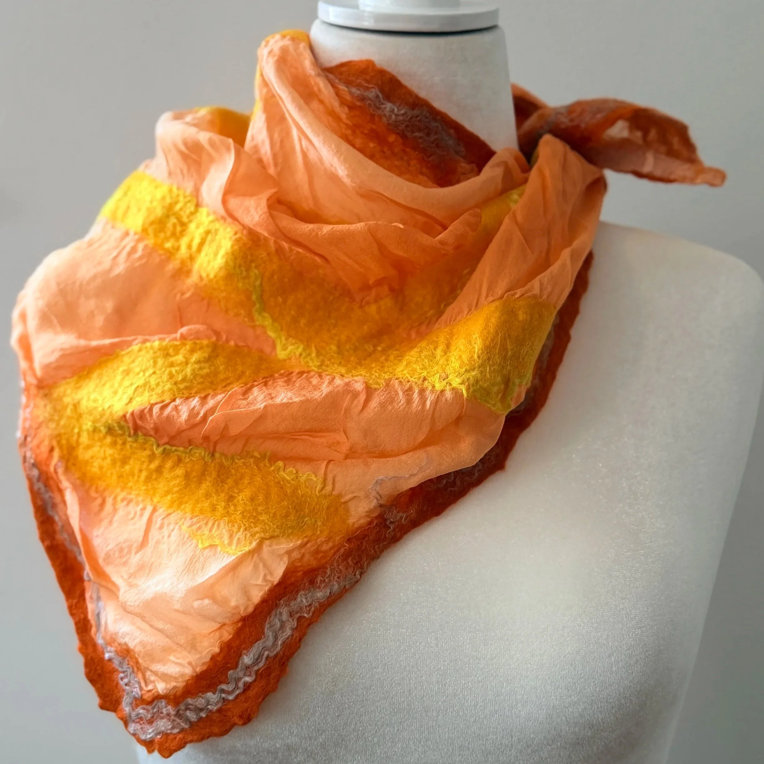 A close-up of a white thermos surrounded by orange and yellow decorative paper resembling a flower, on a light-colored surface.
