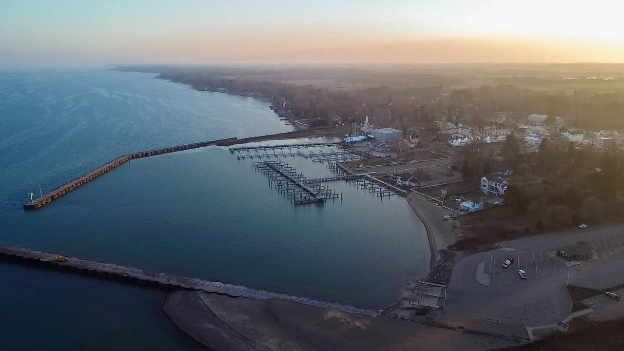 Aerial view of a harbor with docks, water, and a small parking lot at sunset. - Taken by Dillon Morby of D Morby Media, a local photographer working in South East Michigan