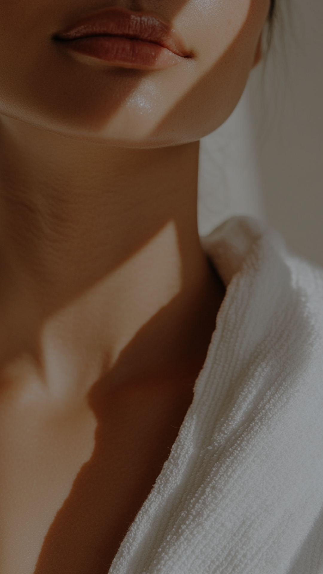 Close-up of a person's face showing lips, chin, and part of a white fabric garment.