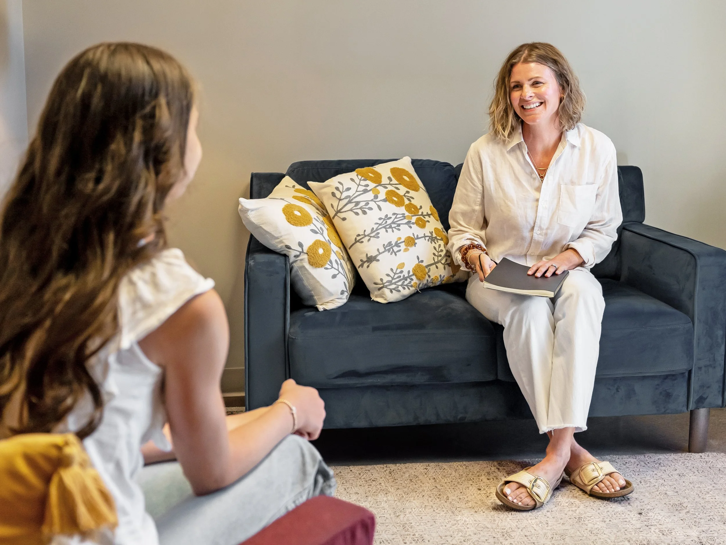A woman talks to a therapist while sitting on a couch.