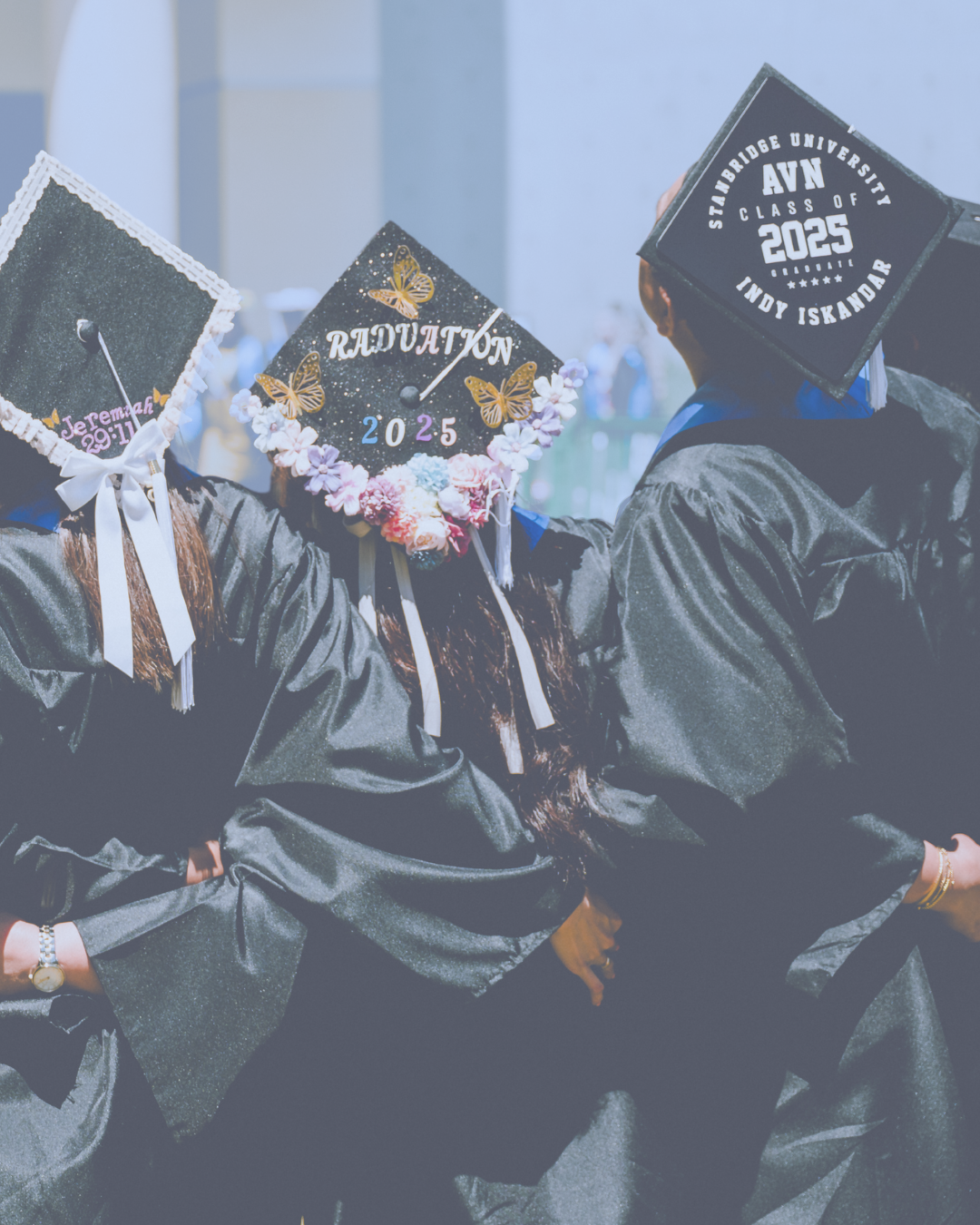 Graduates wearing black gowns and decorated mortarboards at graduation ceremony.