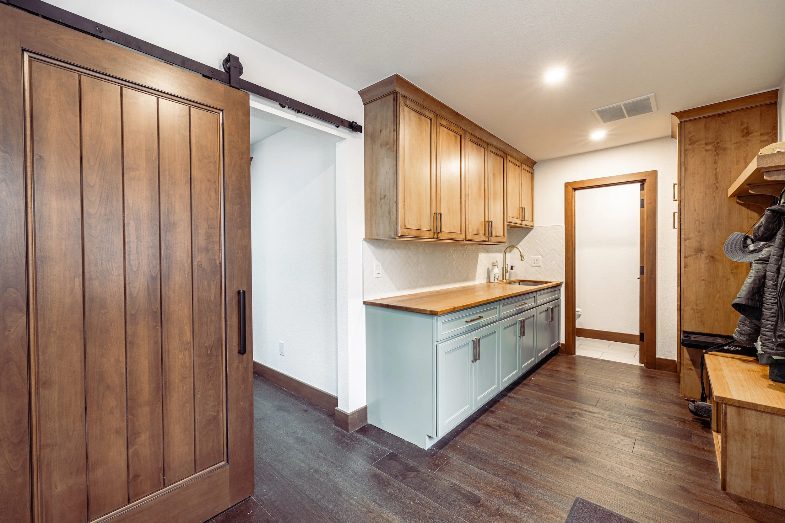 Kitchen with wooden cabinets, dark wood flooring, and a white and light blue lower cabinet with a wooden countertop.