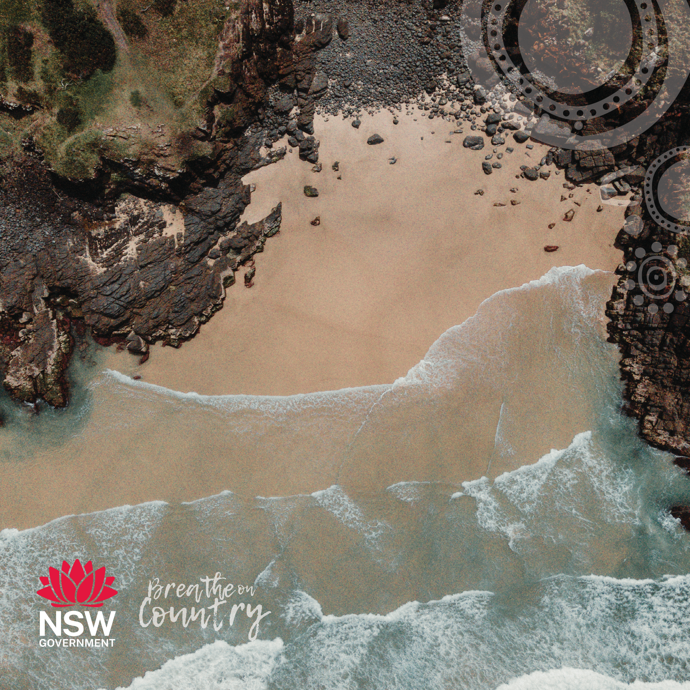 Image of sandy beach, with rocky outcrops and sea running up the beach. Image is taken from over head, looking down at the landscape.
