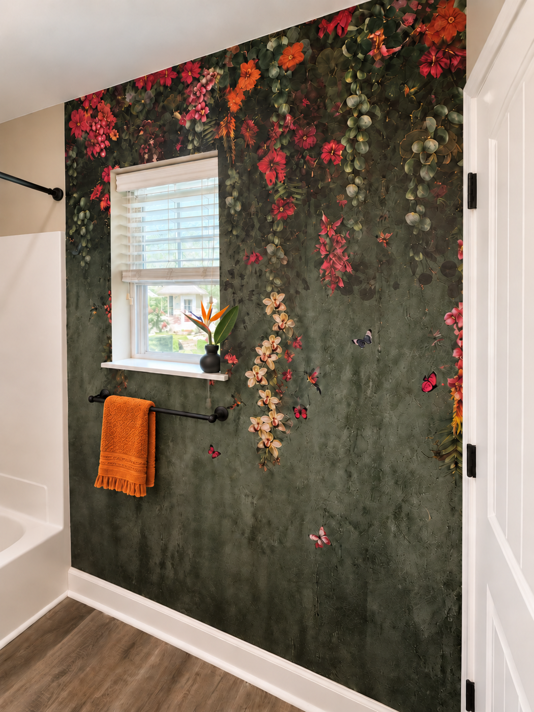 Decorative bathroom wall with floral and butterfly mural, window with blinds, black towel rack with an orange towel, and a small vase with orange and yellow flowers on the window sill.