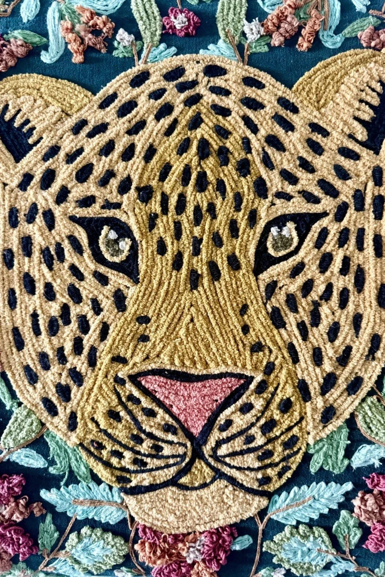 Close-up of a detailed embroidered tiger face artwork with flowers and leaves surrounding it.