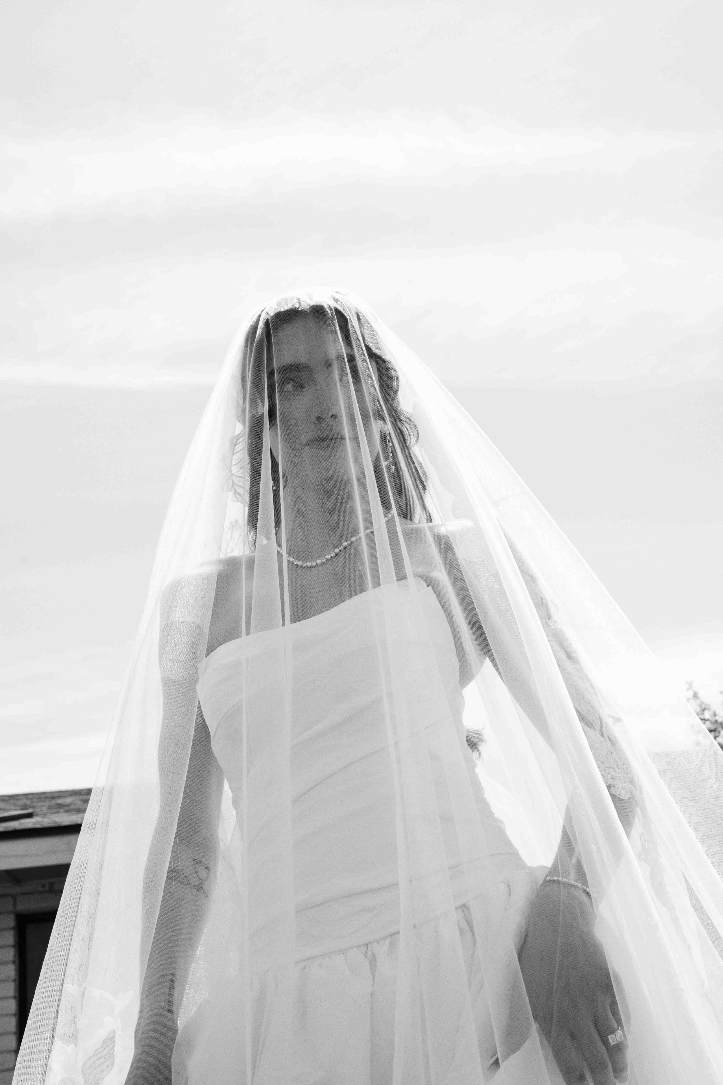 A woman in a wedding dress with a veil outdoor during the day.
