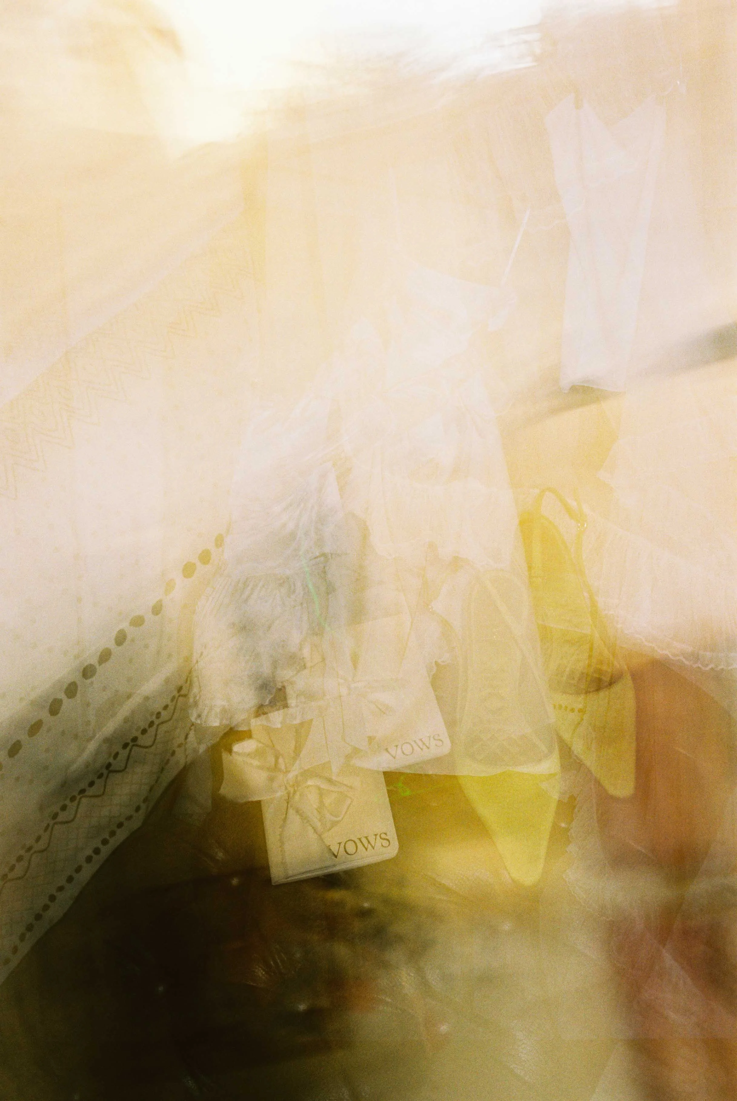 A blurry image of scattered papers and objects on a surface, including vows and what appears to be a shoelace. The image has a yellowish tint and is difficult to discern clearly.