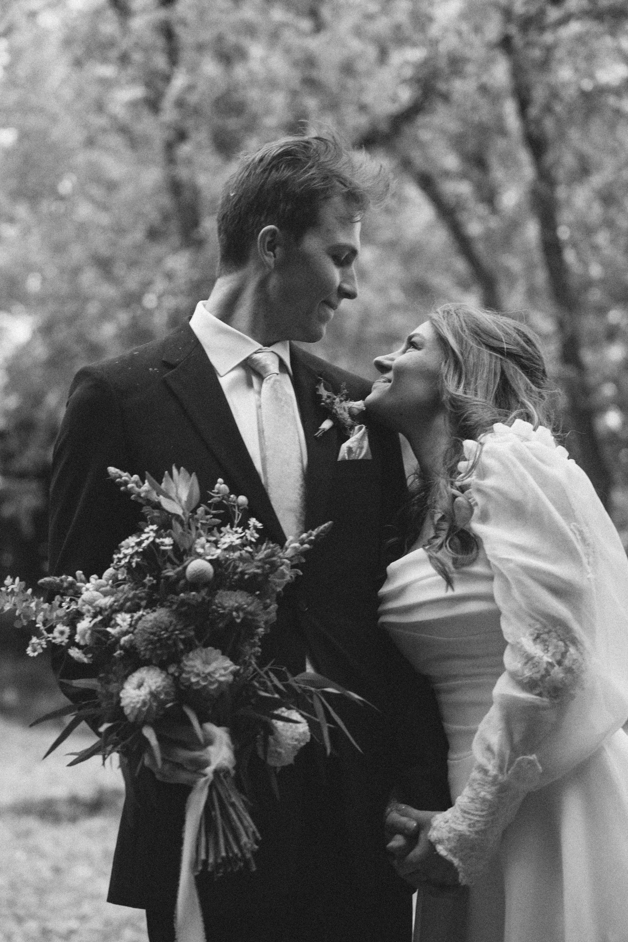 young couple share an intimate moment smiling at each other on their wedding day.
