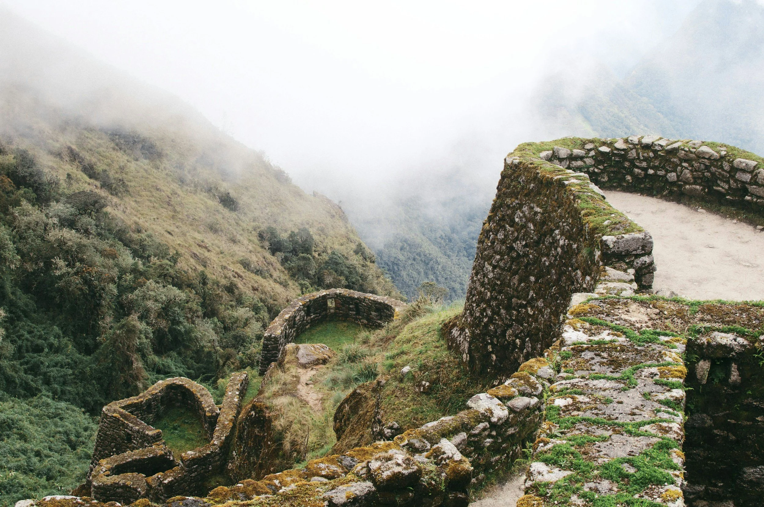 Ancient stone terraces and ruins on a mountain landscape shrouded in mist and fog.