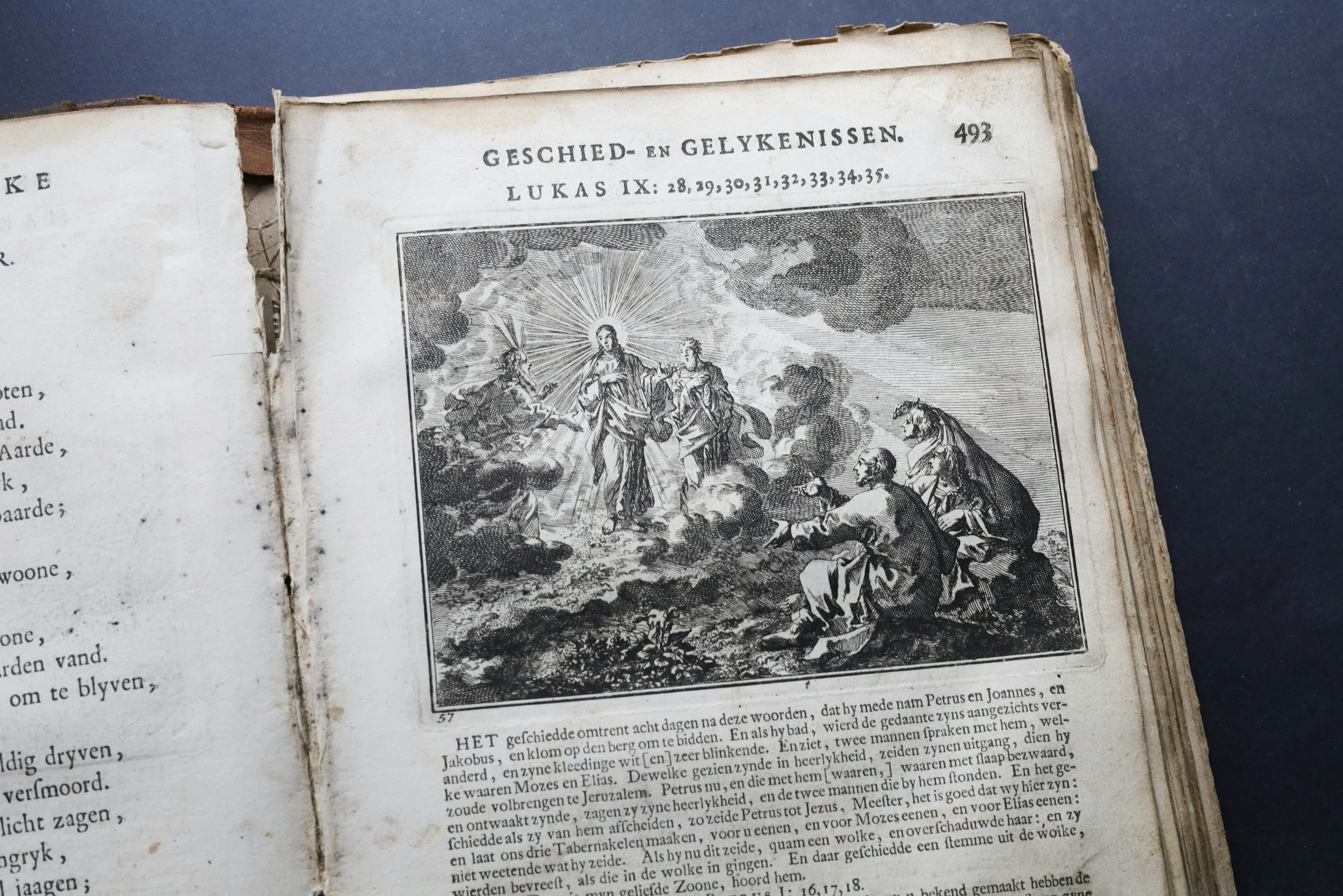 An open antique book with a black and white illustration depicting a biblical scene, with text in a foreign language.