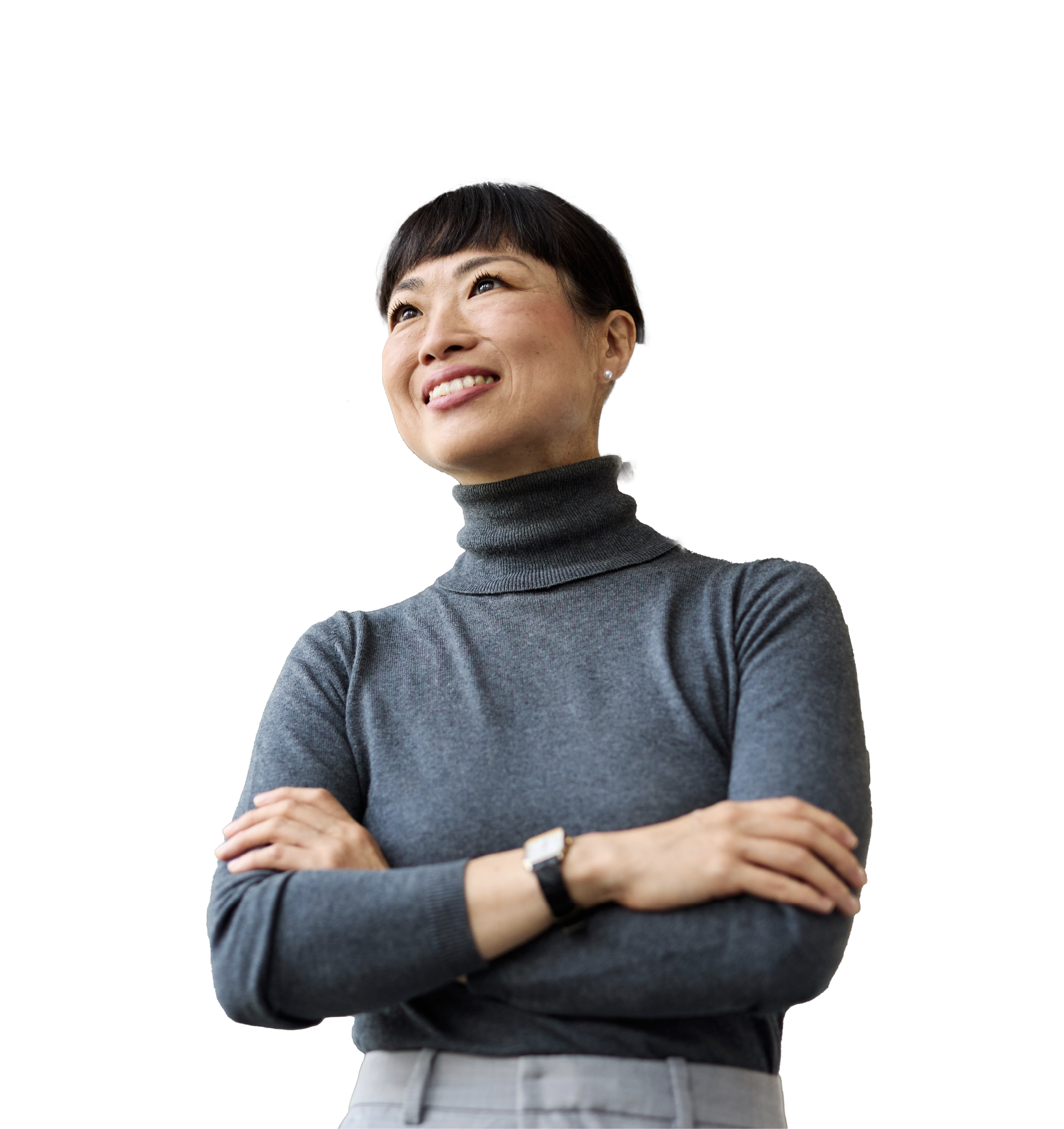 A woman in a gray turtleneck sweater standing with her arms crossed, smiling, against a black background.