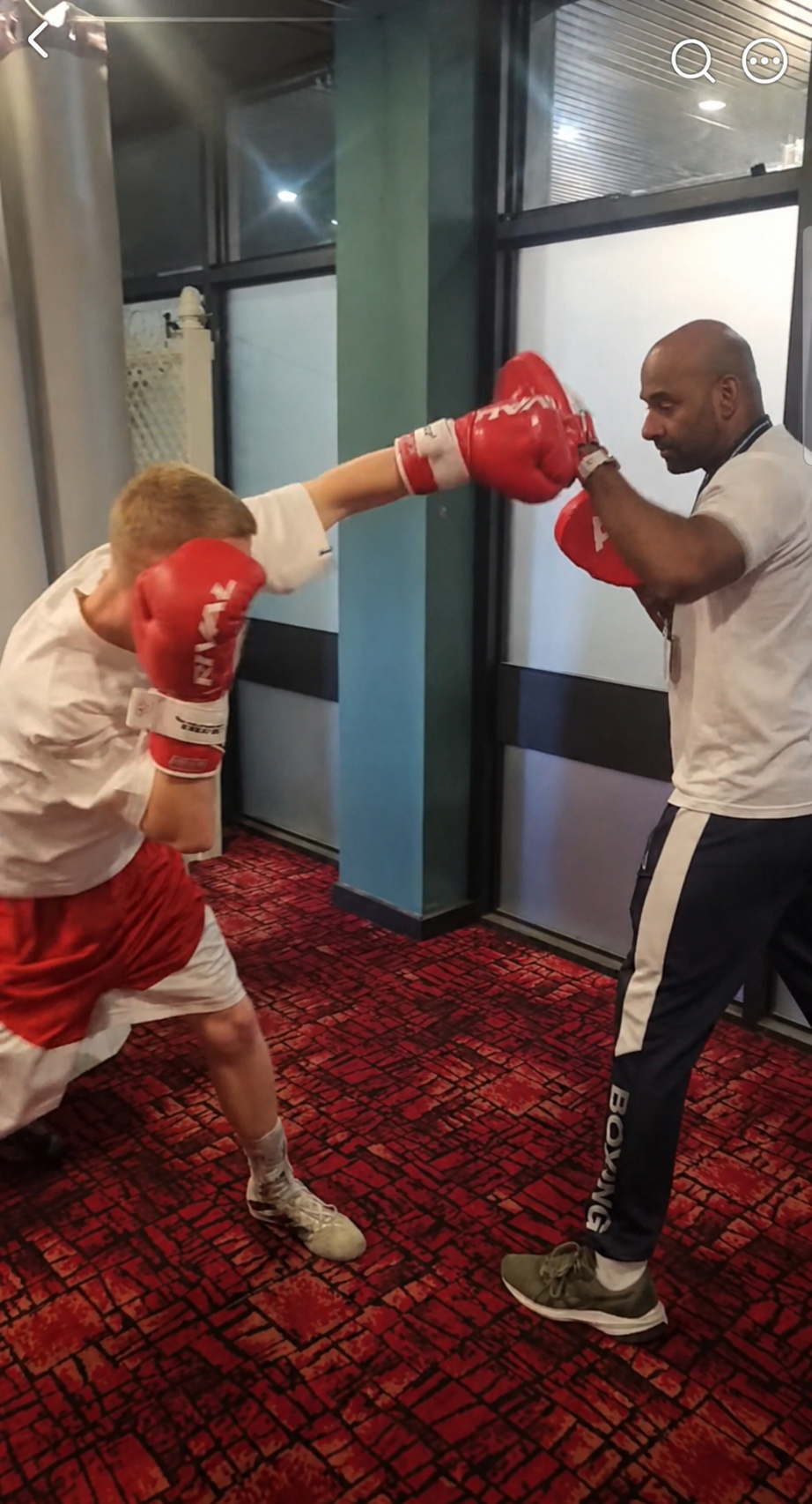 Young boxer practising punching technique with a boxing coach