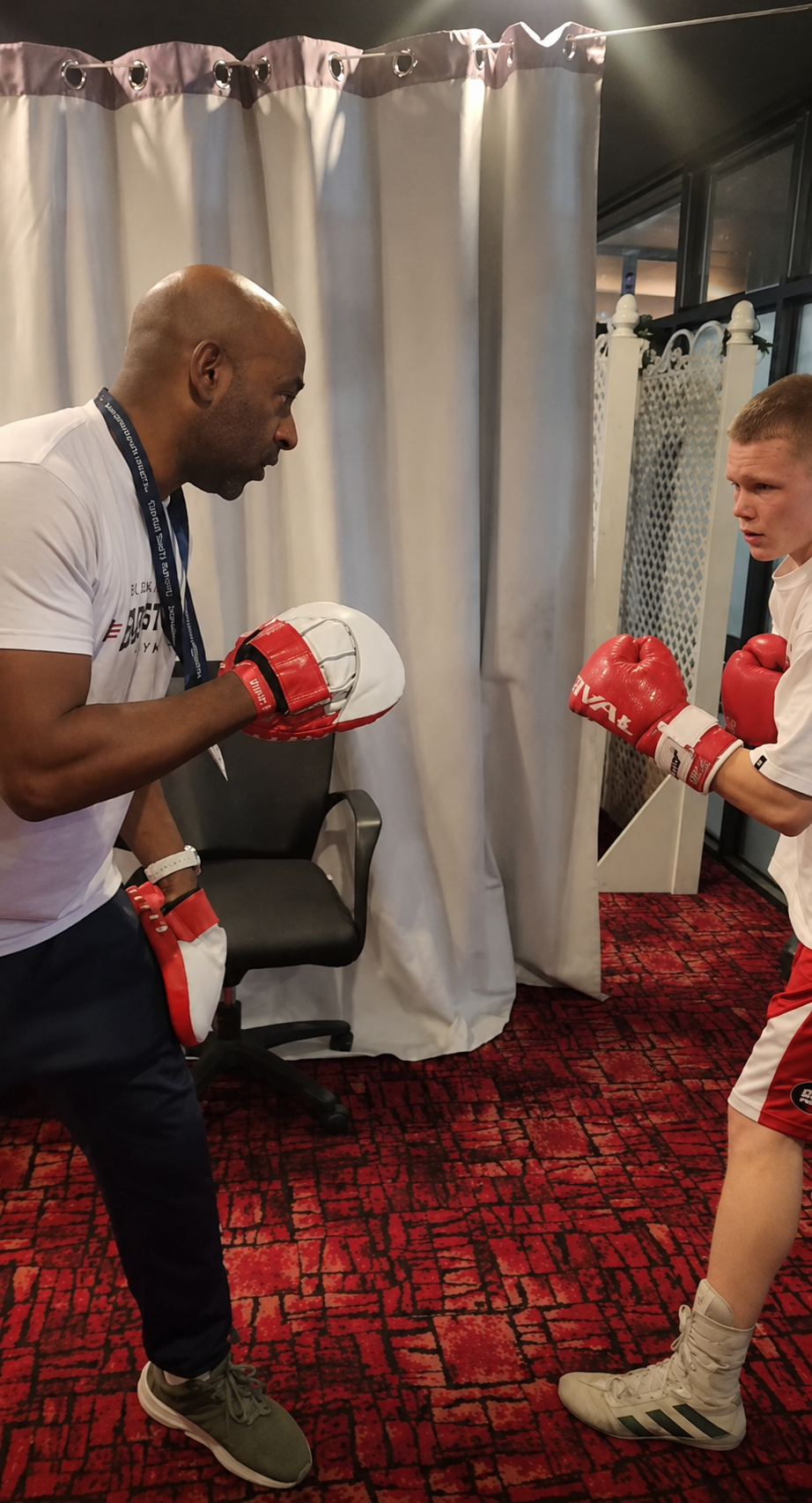 Boxing coach working with a young boxer during a pad training session
