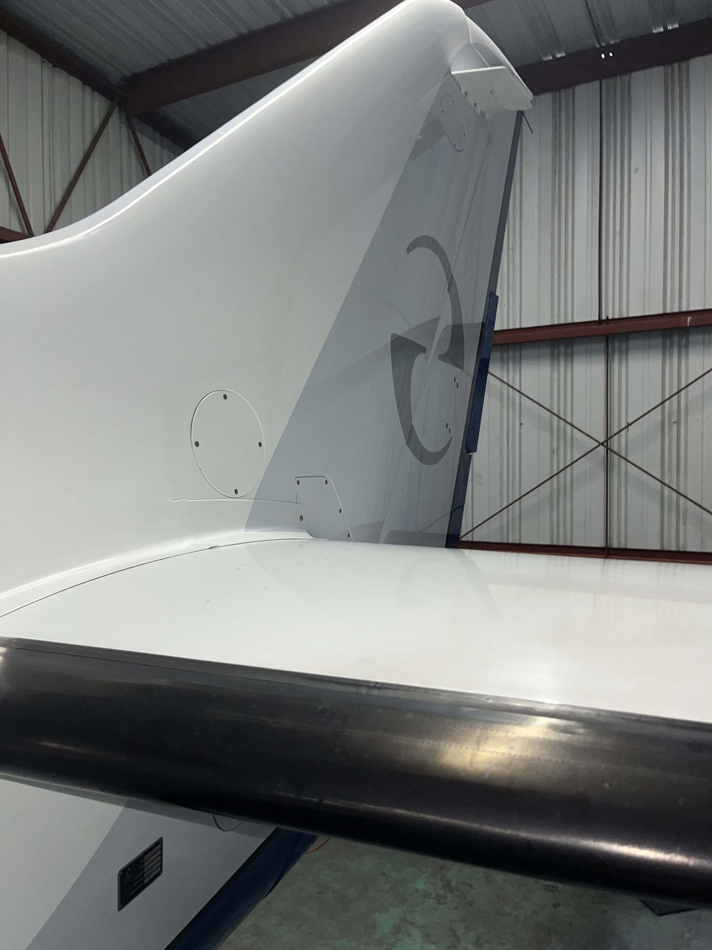 Close-up of the nose section of a white airplane aircraft inside a hangar with metal walls.