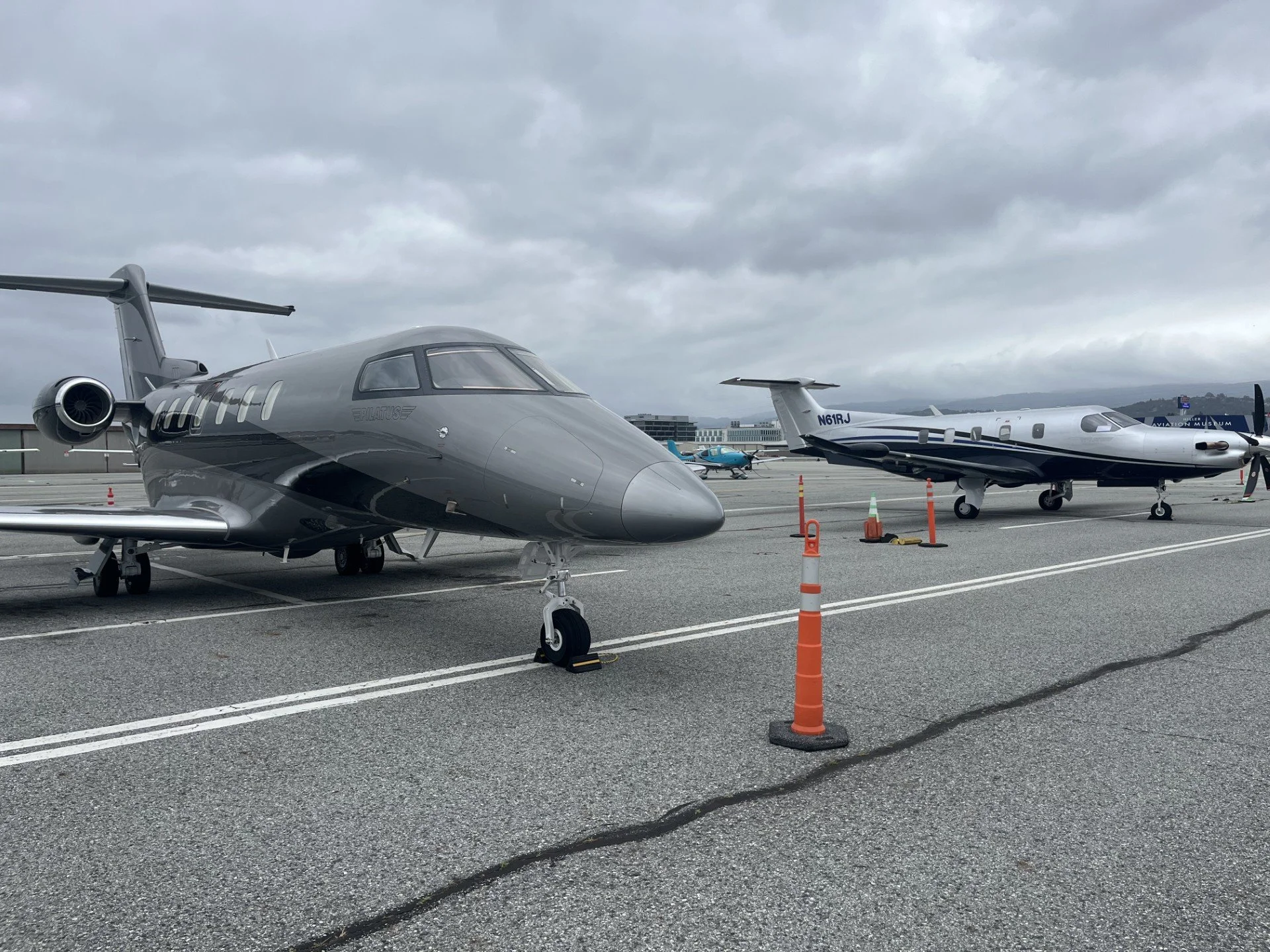 Multiple private jets parked on the tarmac at an airport under cloudy sky.