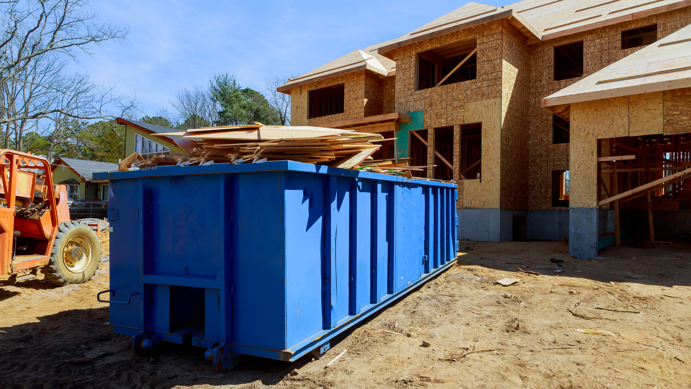 blue roll-off dumpster in front of a newly construction house in a neighborhood