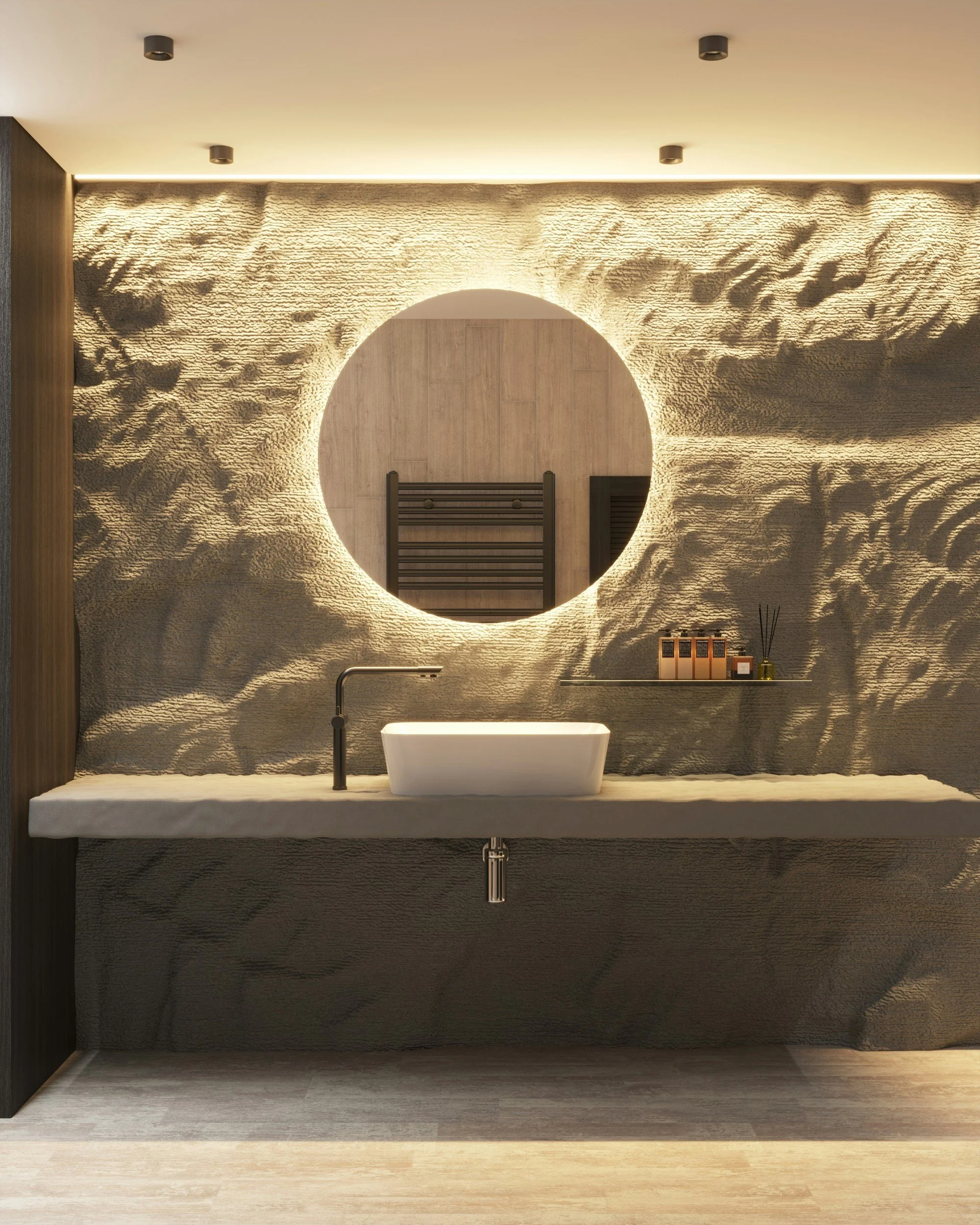 Backlit round mirror above a stone vanity with a vessel basin