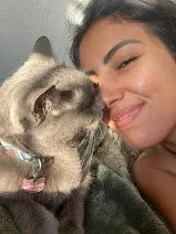 Una joven sonriendo junto a un gato gris