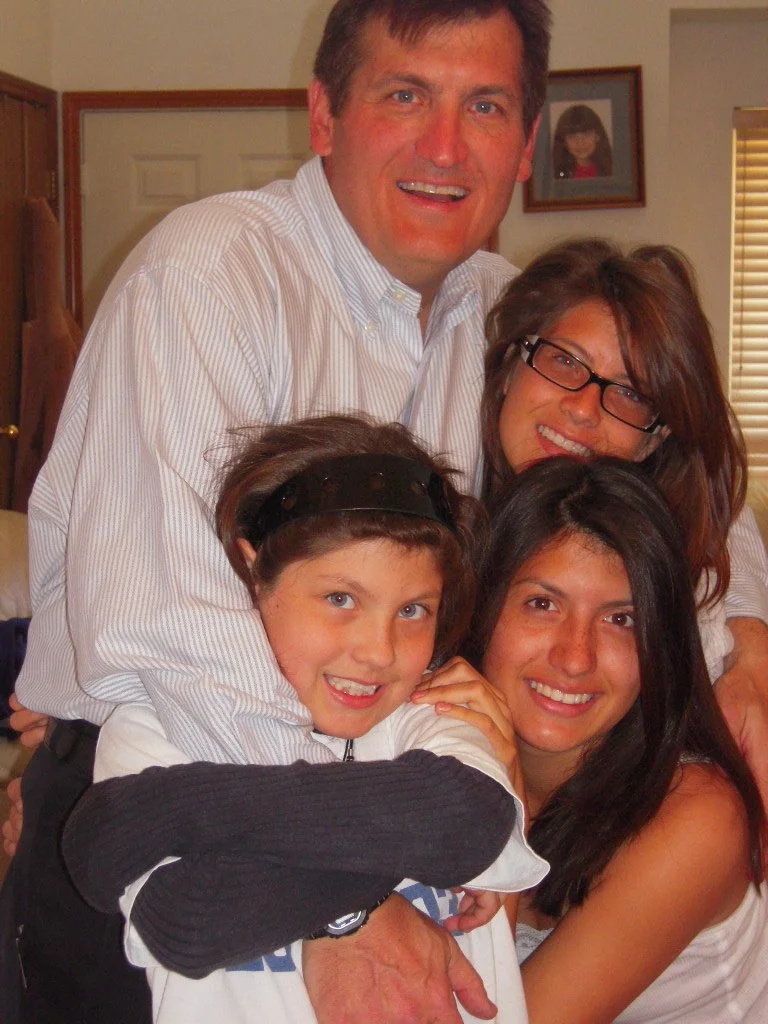 A family of five smiling and posing together indoors.
