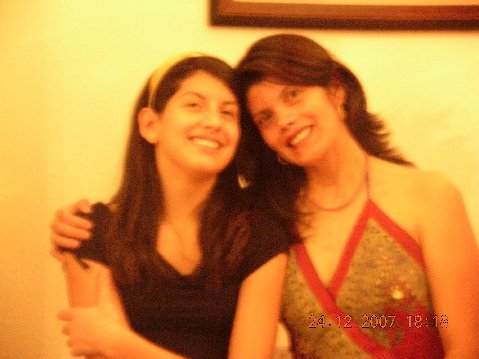 Two women smiling and hugging each other indoors.