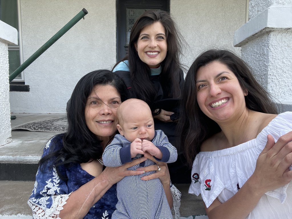 Four women and a baby smiling for a photo on front steps of a house.