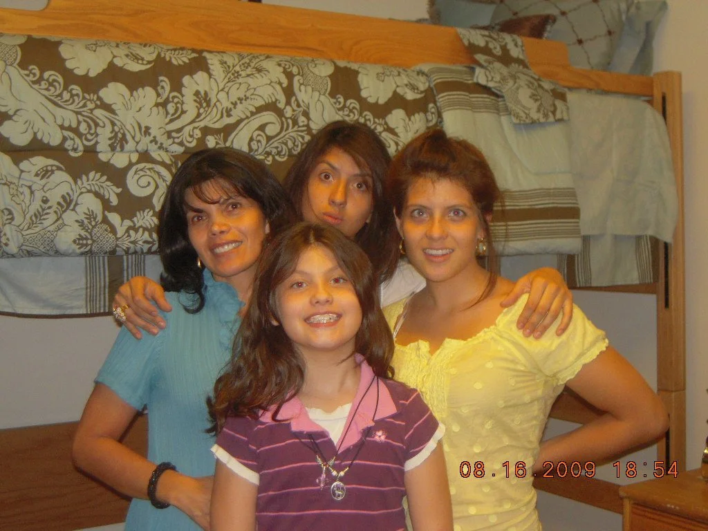 A group of four women smiling and posing for a photo in front of a bunk bed in a bedroom.