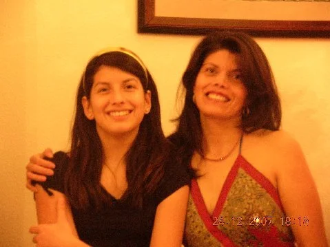 Two women smiling and posing together indoors.